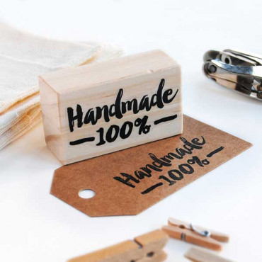 A wooden stamp reading "Handmade 100%" elegantly imprinted on a kraft tag, showcasing the charm of artisan crafts.