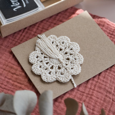 Separador de libros artesanal en ganchillo, con forma de flor y colores neutros para un toque elegante.