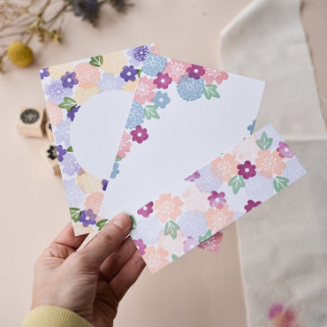 Hand holding all the creations: handmade postcards, bookmark, and floral stamps, showcasing your DIY projects.