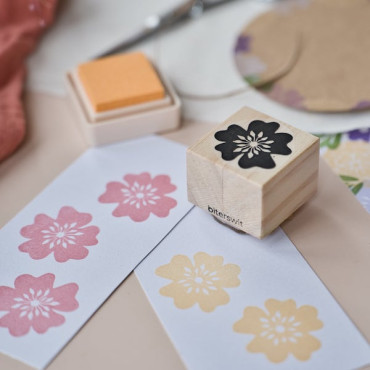 Primer plano del sello de flor de cerezo dejando una elegante impresión floral en etiquetas blancas para tus creaciones DIY.