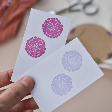 Close-up of two white tags with detailed peony print in burgundy and pale lilac ink.