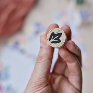 Hand holding a mini botanical stamp with a delicate leaf design, perfect for creative projects.