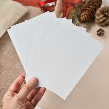 A hand holding a white postcard, showing its smooth texture and sturdy thickness.